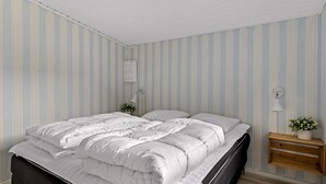 Une chambre à coucher comprenant un lit, une table de chevet, une lampe et un luminaire fixé au mur.