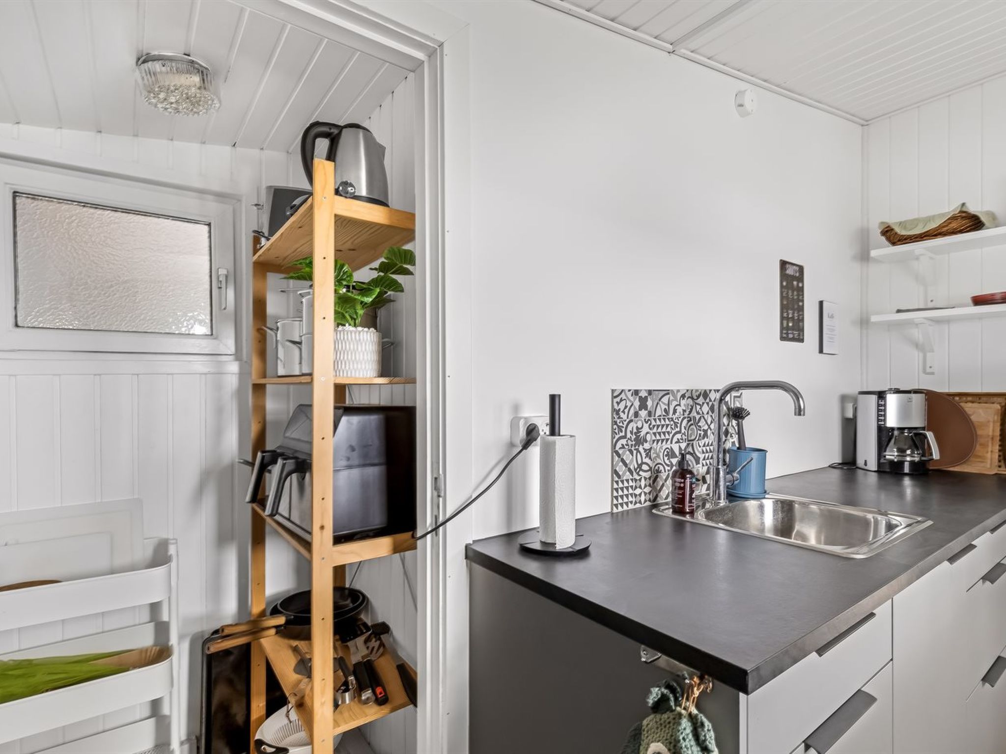 A modern kitchen with a built-in shelf unit, a coffee maker, and a sink.