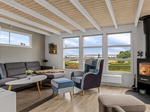 A modern living room with a sofa, armchairs, a coffee table, and a fireplace.