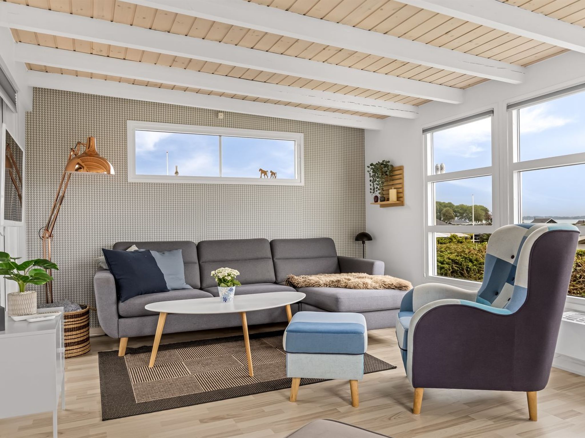 Ein modernes Wohnzimmer mit einem grauen Sofa, einem runden Couchtisch und einem blauen Sessel.