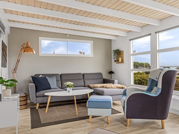 A modern living room with a grey sofa, a round coffee table, and a blue armchair.