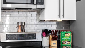 Une cuisine équipée d’un four à micro-ondes, d’un four traditionnel et d’un livre de recettes posé sur le plan de travail.