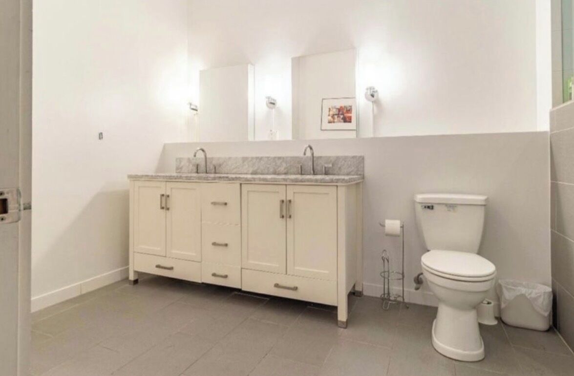 Een badkamer met een wit toilet, een kast met lades en een spiegel boven de wastafel.