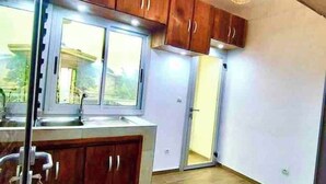 Une cuisine avec des meubles de rangement en bois, une fenêtre et un évier.