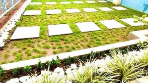 Un jardin sur le toit, composé d’une série de jardinières carrées disposées en réseau et entouré de verdure.