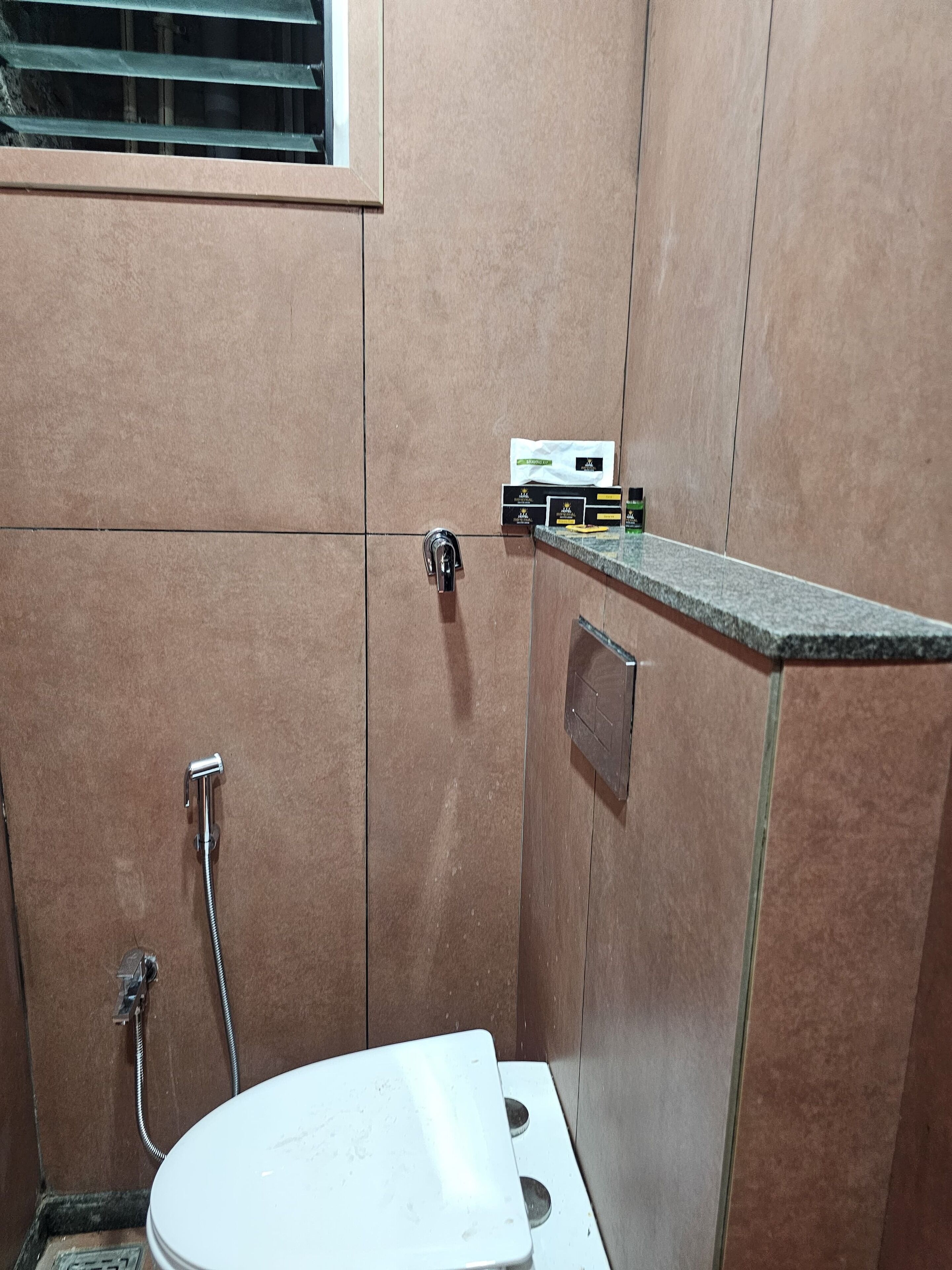 A small bathroom with a toilet, a shower, and a sink. There is a towel dispenser and a soap dispenser on the wall.