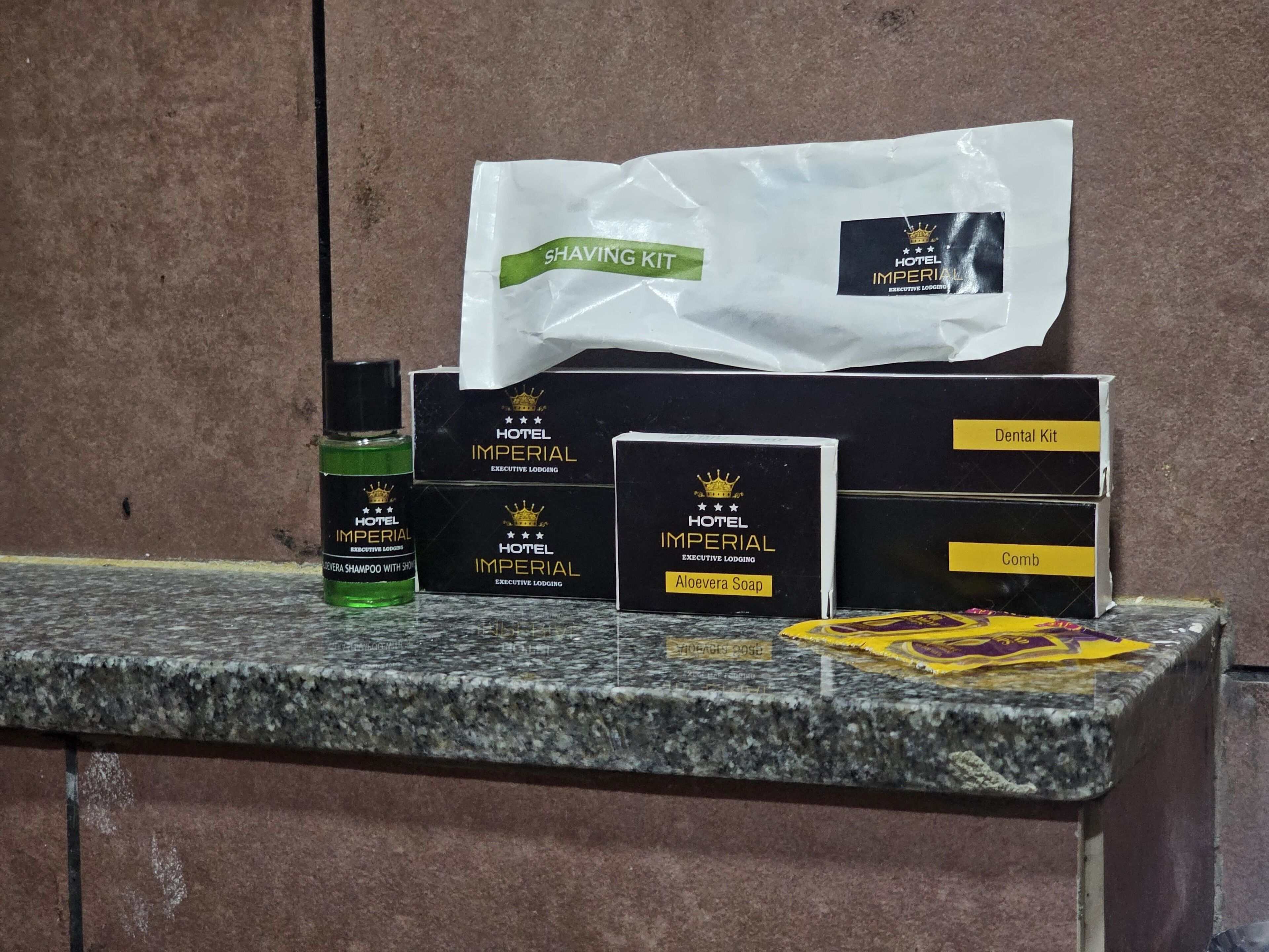 A grooming station with Hotel Imperial Executive Lodging branded items including a shaving kit, dental kit, comb, and aloe vera soap.