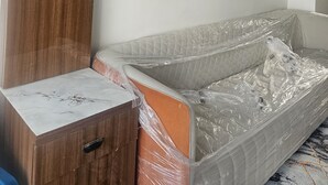 Ein Schlafzimmer mit einem Holfischschrank, einem mit Plastik bezogenen Bett und einem weißen Kopfteil.