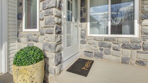 Une maison en pierre avec un paillasson sur lequel est écrit « bonjour » et une petite plante en pot.