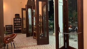 Egy szoba, melynek a padlója mintás, van benne egy könyvespolc, egy szék, és egy ajtó, amely egy kültéri területre nyílik, ahol egy robogó található.