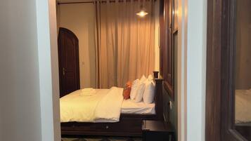 Una habitación de hotel con cama, cortinas, mesita de noche y lámpara.
