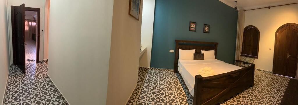 A bedroom with a bed, a wooden headboard, a nightstand, and a mirror.