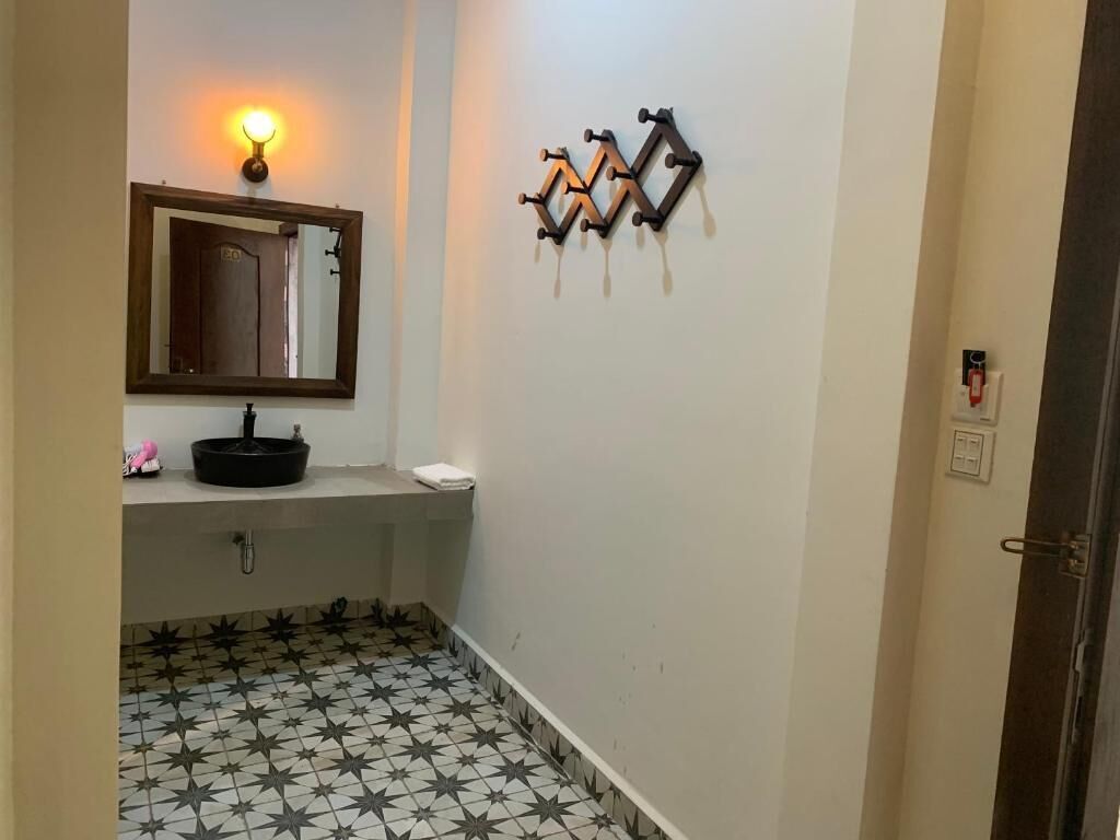 A bathroom with a star-patterned floor, a sink with a mirror above it, and a wall-mounted light fixture.