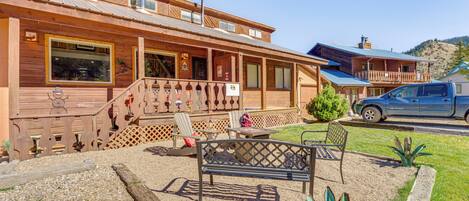 A wooden building with a porch, outdoor seating, and a vehicle parked nearby.