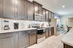 A modern kitchen with dark wood cabinets, stainless steel appliances, and a white countertop. - 14 Mi to WDW: Family-Friendly Home w/ Movie Room! (Kissimmee)