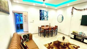 A modern living room with a sofa, a dining table with chairs, a coffee table, and a rug. - African Home Savane  (Douala)
