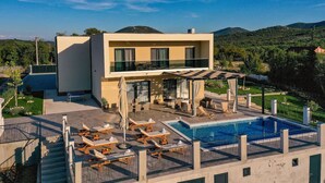 A modern two-story house with a swimming pool, outdoor seating, and a view of the surrounding landscape. - Luxurious Sanctuary Villa Primorski Dolac With Pool (Primorski Dolac)