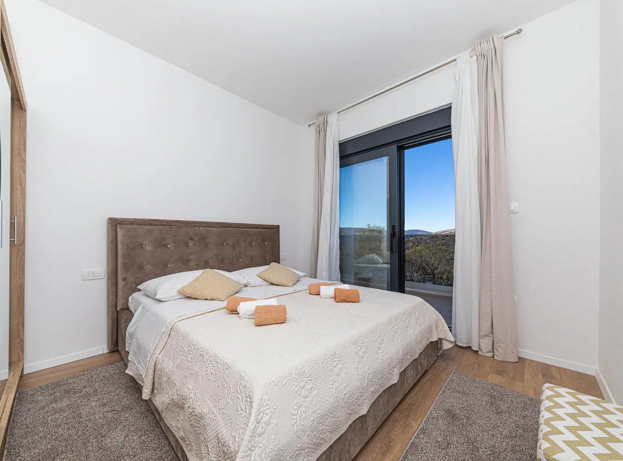 Une chambre avec un grand lit, une fenêtre avec des rideaux et une vue sur l’extérieur.
