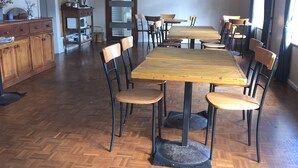 A dining area with a large wooden table surrounded by chairs, a kitchen area with wooden cabinets, and a painting on the wall.