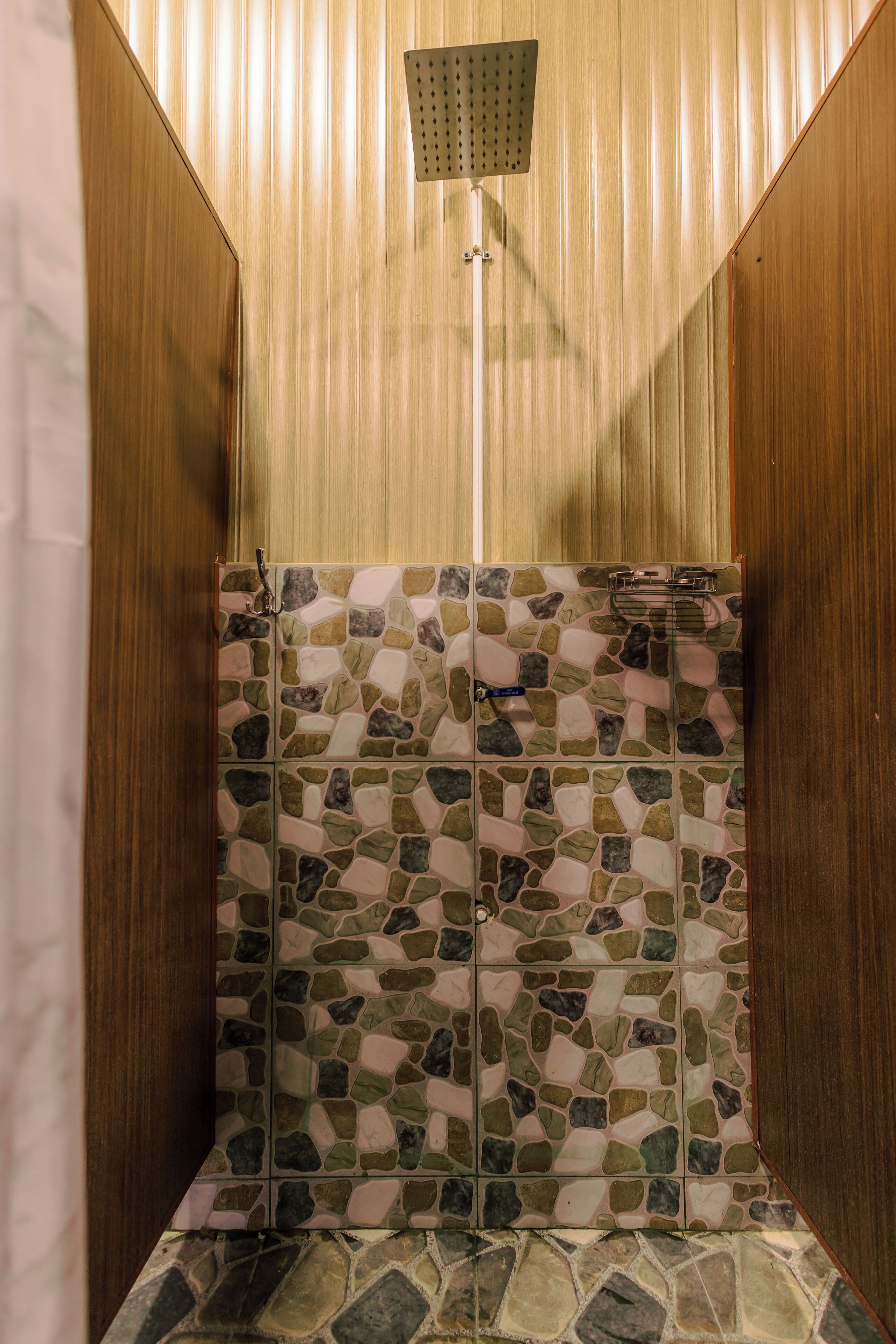 Una ducha con pared de mosaico y paneles de madera.