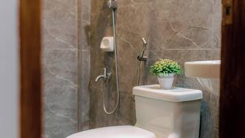 Un bagno con il water, una doccia e una piccola pianta in vaso.