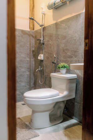 Ein Badezimmer mit Toilette, Dusche und einem kleinen Topfpflanzen.
