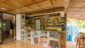 A store with shelves stocked with snacks and beverages, a fan, and a counter with a basket. - BUSAI DREAM FALLS RESORT (Sevilla)