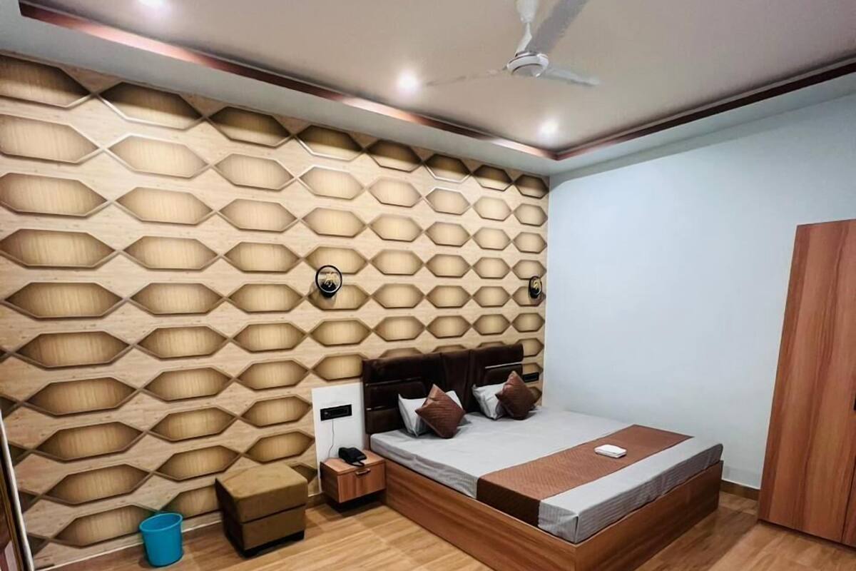 A modern bedroom with a geometric-patterned wall, a bed with a wooden headboard, a nightstand, and a wardrobe.