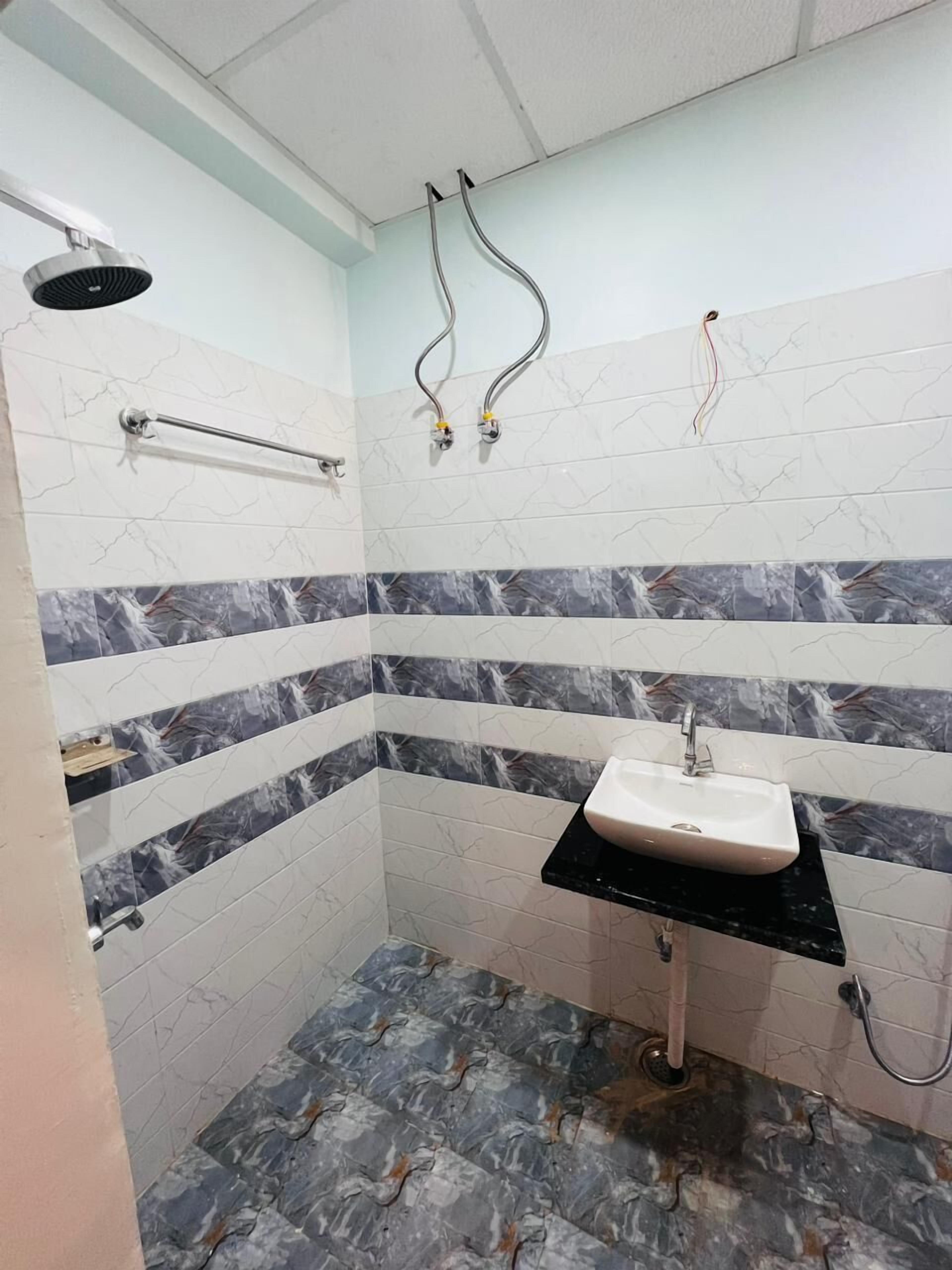 Ein Badezimmer mit weiß-grauem Marmorfliesendesign, einem schwarzen Waschtisch und einer Handbrause.