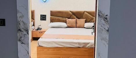 A bedroom with a bed, nightstand, and wall-mounted phone.