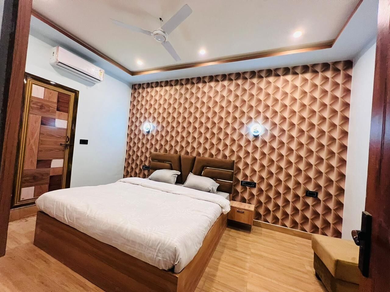 A bedroom with a wooden bed, a ceiling fan, an air conditioning unit, and a textured wall.