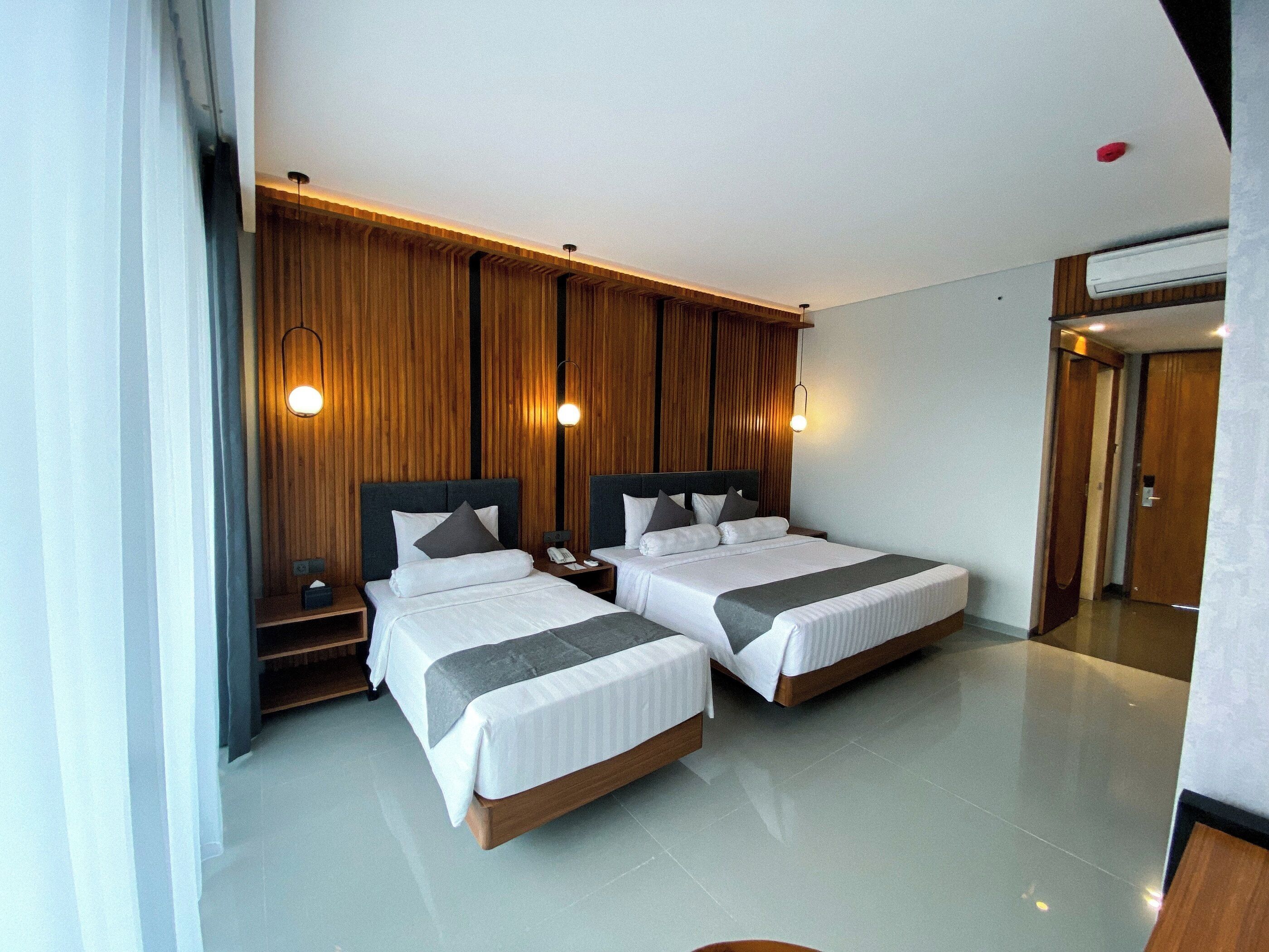 A modern hotel room with two beds, wooden paneling, and a large mirror.