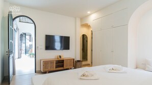 A modern hotel room with a large bed, a TV mounted on the wall, a wardrobe, and a small wooden cabinet. - Oxygen Valley Khao Yai B2 (Pak Chong)