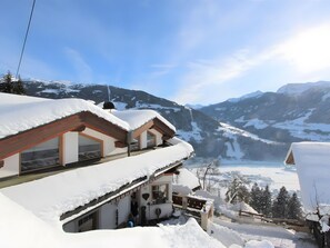 A snow-covered chalet with a balcony, a wooden roof, and a view of snow-capped mountains. - Apartment 'Melissa' with Mountain View, Balcony and Wi-Fi (Zellberg)