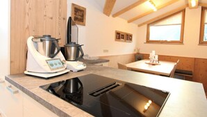 A modern kitchen with a built-in induction cooktop, a coffee maker, and a kettle. - Apartment 'Melissa' with Mountain View, Balcony and Wi-Fi (Zellberg)