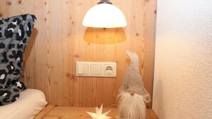 A wooden wall with a white switchboard, a white lamp, and a small gnome figurine. - Apartment 'Melissa' with Mountain View, Balcony and Wi-Fi (Zellberg)