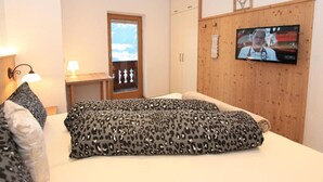 A bedroom with a bed, a television, a window, and a wooden wardrobe. - Apartment 'Melissa' with Mountain View, Balcony and Wi-Fi (Zellberg)
