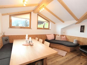 A cozy room with a wooden table, bench seating, and large windows with a view of the outdoors.