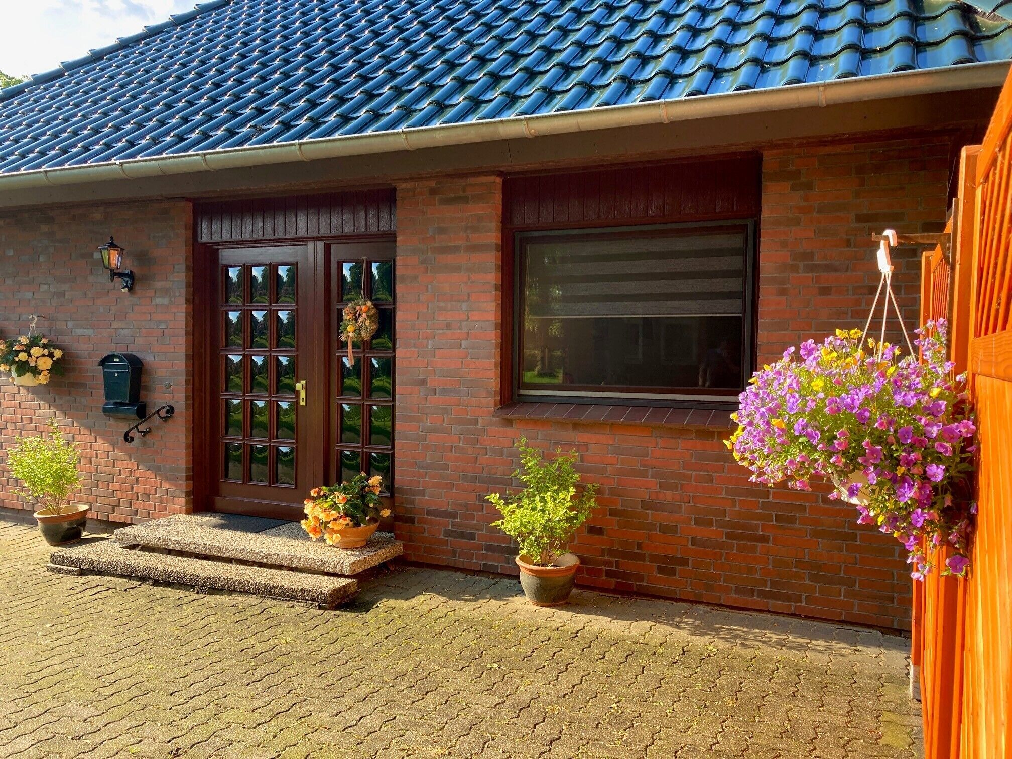 A brick house with a tiled roof, a front door, and potted plants.