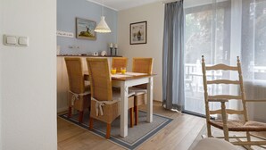A dining area with a table, chairs, and a window with curtains. - Apartment 'Hoper Mühle' with Balcony and Wi-Fi (Sankt Michaelisdonn)