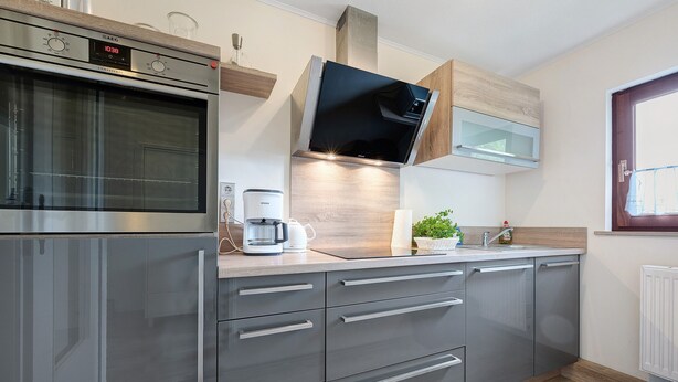A modern kitchen with a built-in oven, a coffee maker, and a microwave. - Apartment 'Hoper Mühle' with Balcony and Wi-Fi (Sankt Michaelisdonn)