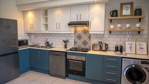 Una cocina moderna con electrodomésticos de acero inoxidable, armarios azules y lavadora integrada.