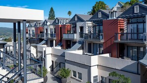 Un moderno edificio de apartamentos con varios balcones, ventanas amplias y una vista despejada del paisaje circundante.