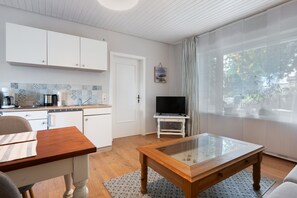 A modern kitchen with white cabinets, a coffee maker, and a television on a stand.