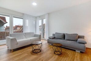 Un salon spacieux avec deux canapés, une table basse et de grandes fenêtres.
