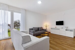 Un salon moderne avec un canapé, une table basse, un téléviseur et un meuble blanc.