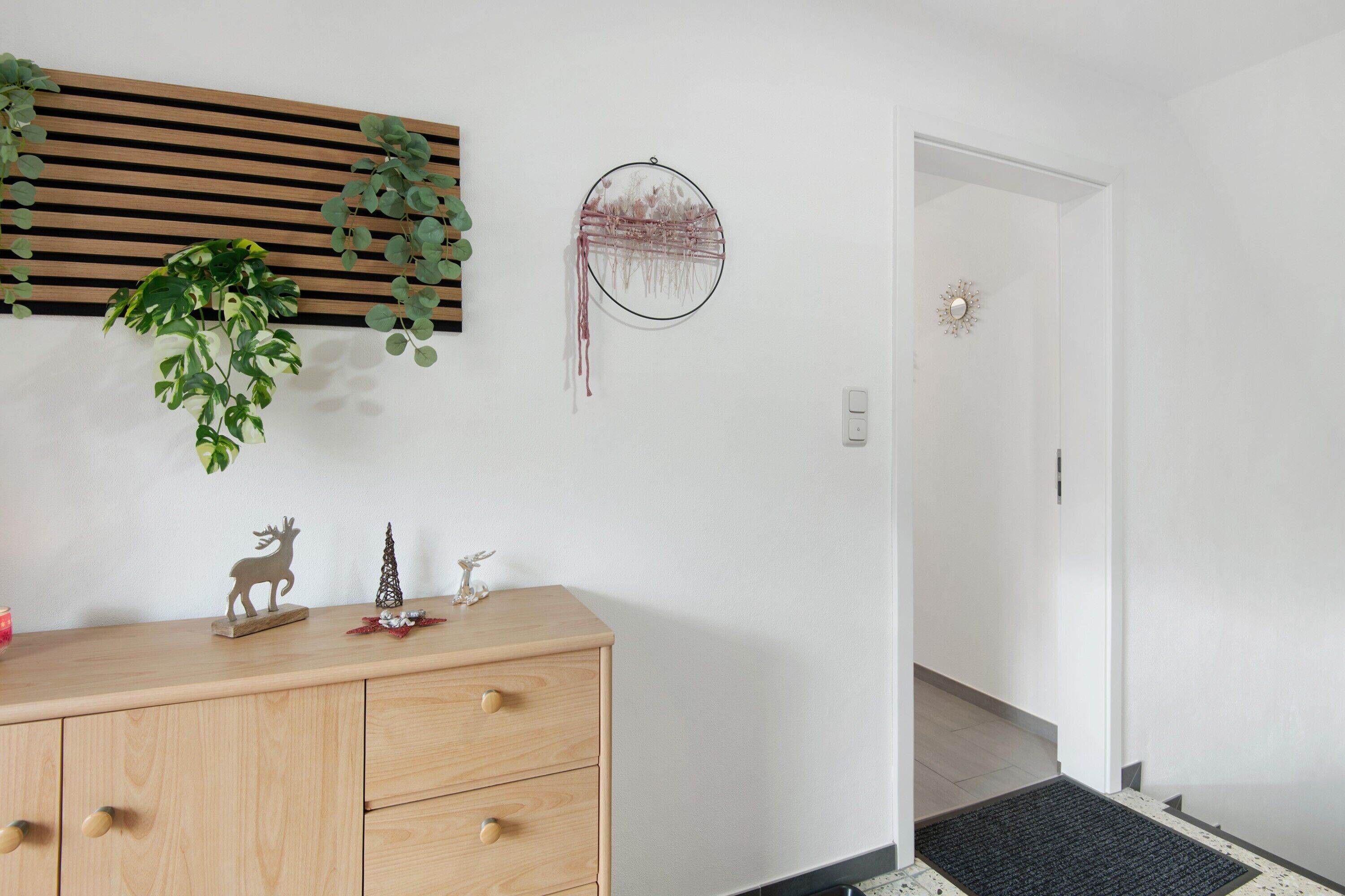 Een kamer met een houten dressoir, een droomvanger en een plant.