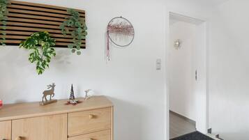 Een kamer met een houten dressoir, een droomvanger en een plant.