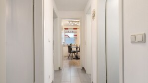 Un pasillo estrecho que desemboca en un comedor, con una mesa y sillas.