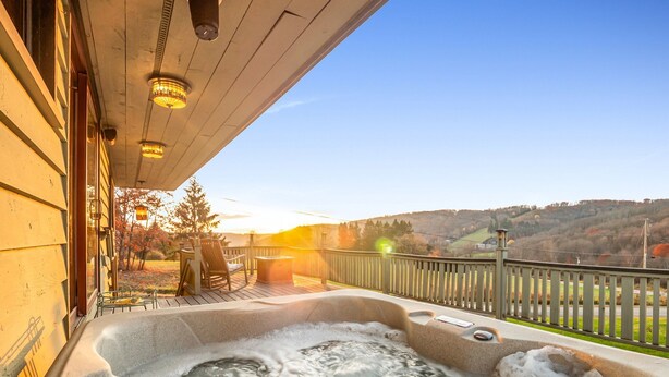 A hot tub on a wooden deck with a view of a hilly landscape. - The Eagles Nest – Couples Escape - Hot Tub & Views! (Ellicottville)